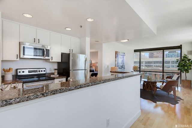 kitchen featuring dark stone countertops, white cabinetry, floor to ceiling windows, and appliances with stainless steel finishes