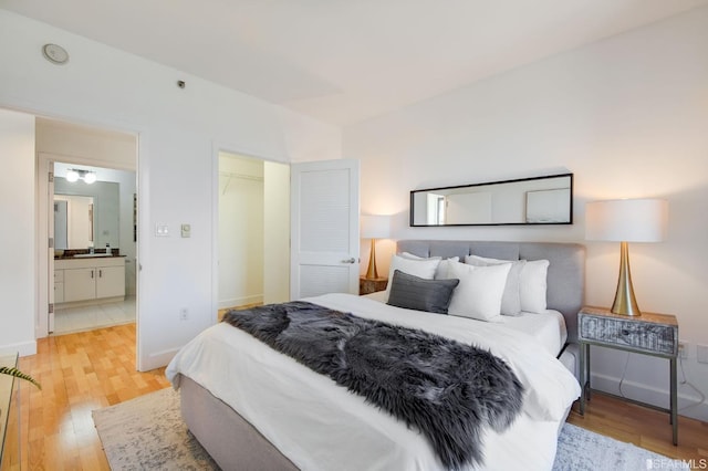 bedroom with a closet, ensuite bathroom, light hardwood / wood-style flooring, and a spacious closet