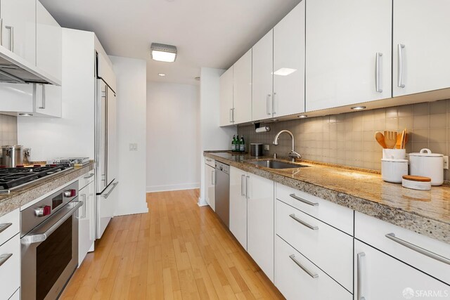 188 Minna St Unit 24A, San Francisco, CA 94105 - kitchen with appliances with stainless steel finishes, a sink, light wood finished floors, white cabinetry, and decorative backsplash