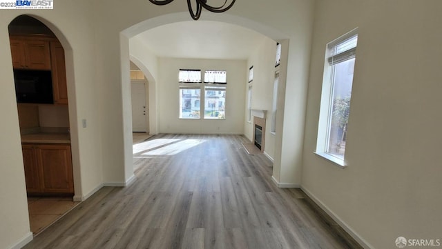 hallway with an inviting chandelier, a healthy amount of sunlight, and light hardwood / wood-style floors