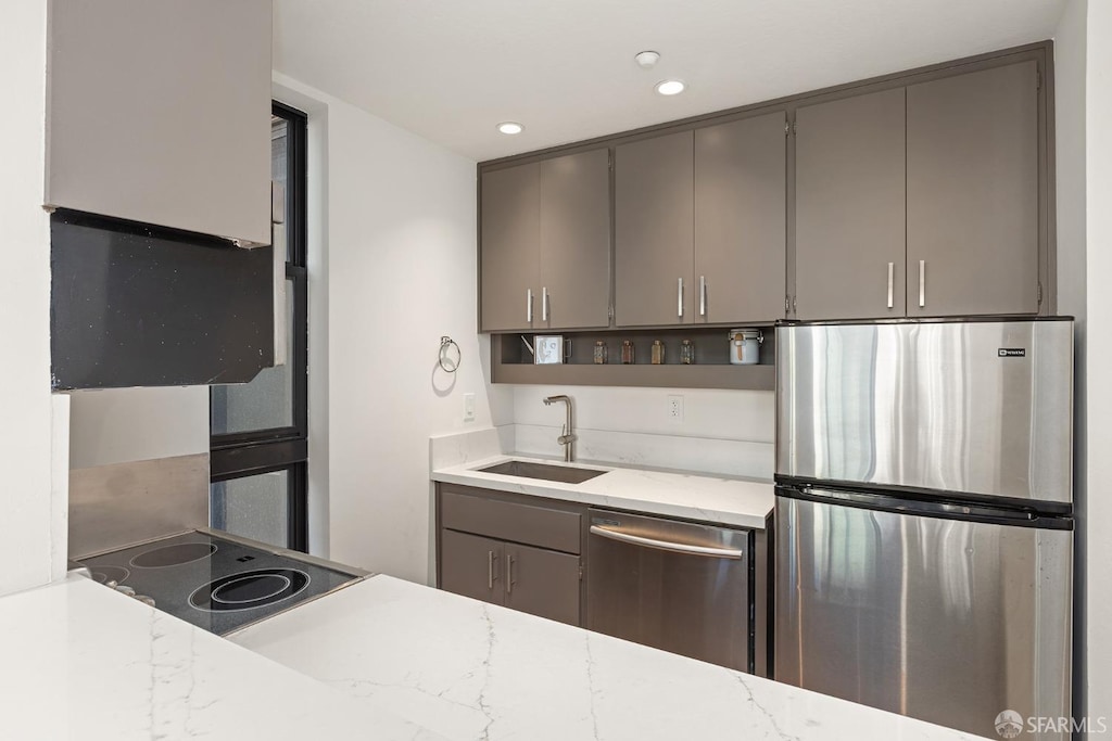 kitchen featuring gray cabinetry, sink, light stone countertops, and stainless steel appliances