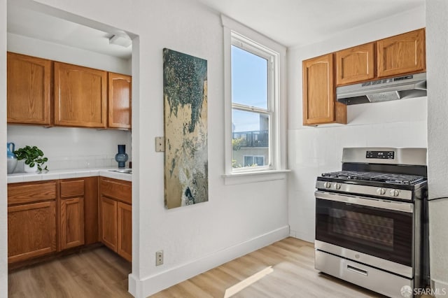 77 Reddy St, San Francisco, CA 94124 - kitchen featuring gas range, under cabinet range hood, light wood-style flooring, and brown cabinets