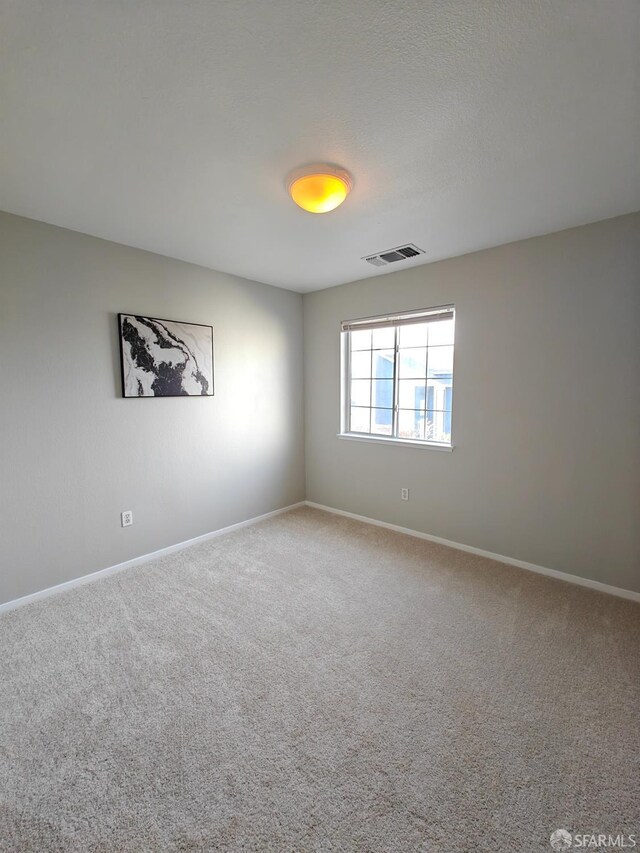 empty room with baseboards, visible vents, and carpet flooring