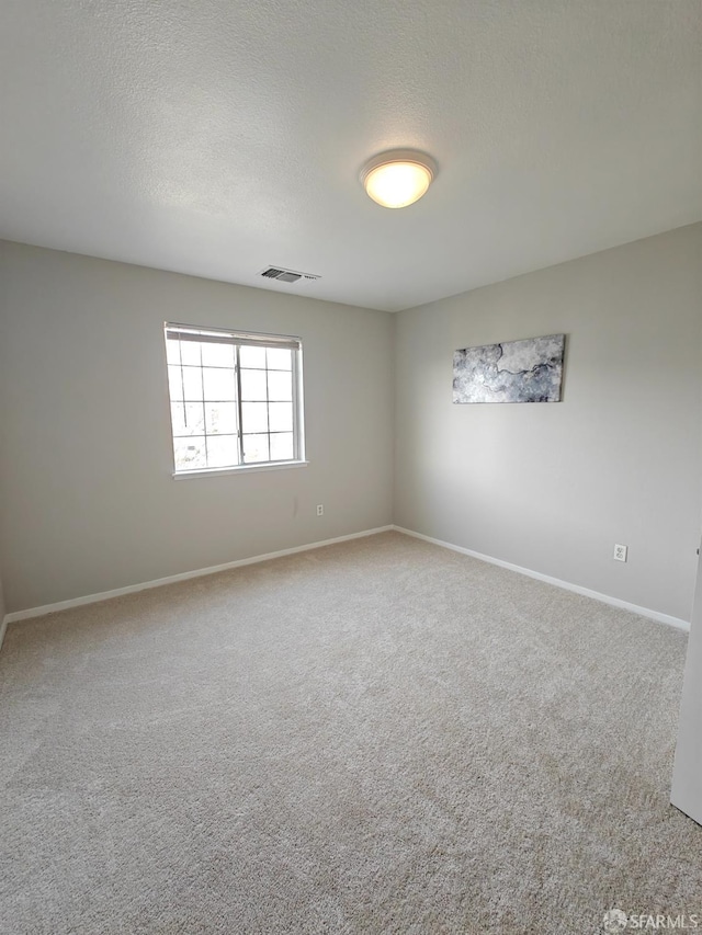 carpeted empty room featuring a textured ceiling, visible vents, and baseboards