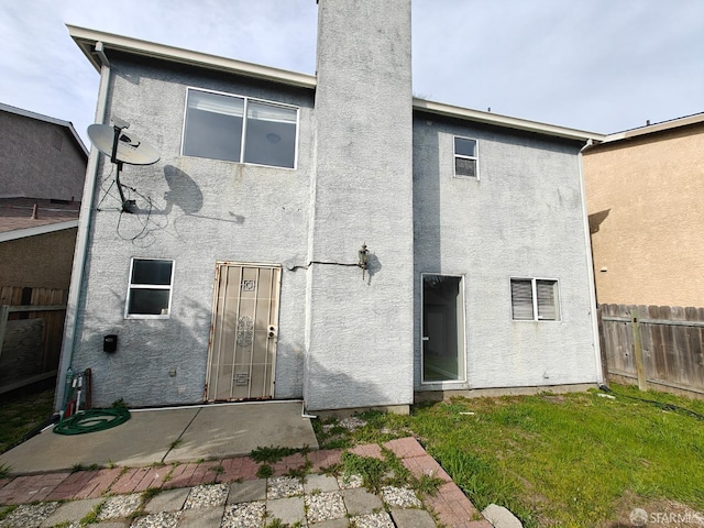 back of property with a patio area, fence, a lawn, and stucco siding