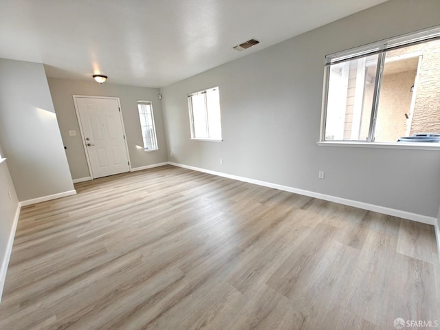 unfurnished room featuring baseboards, visible vents, and light wood-style floors