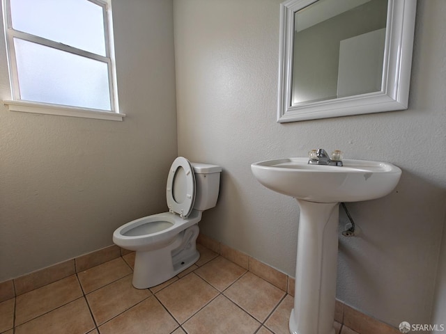 half bathroom featuring tile patterned flooring, baseboards, and toilet