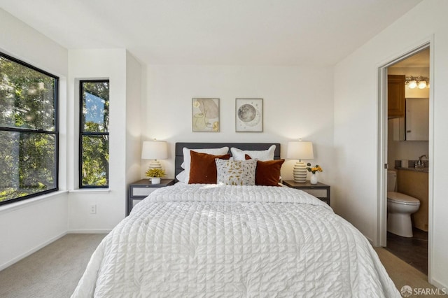 carpeted bedroom with sink and ensuite bathroom