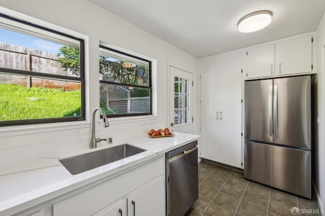 kitchen featuring sink, stainless steel appliances, white cabinets, and light stone countertops