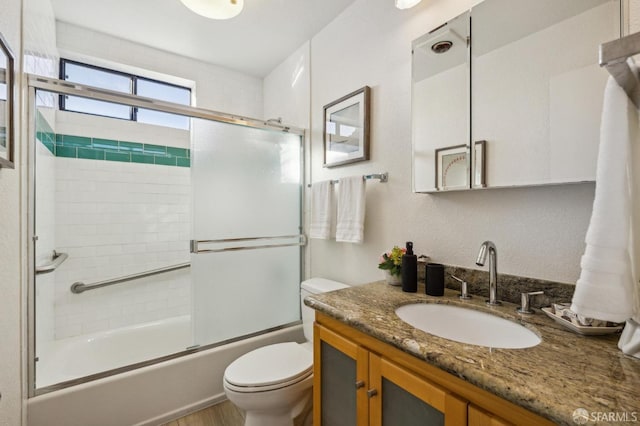 full bathroom featuring toilet, vanity, and bath / shower combo with glass door