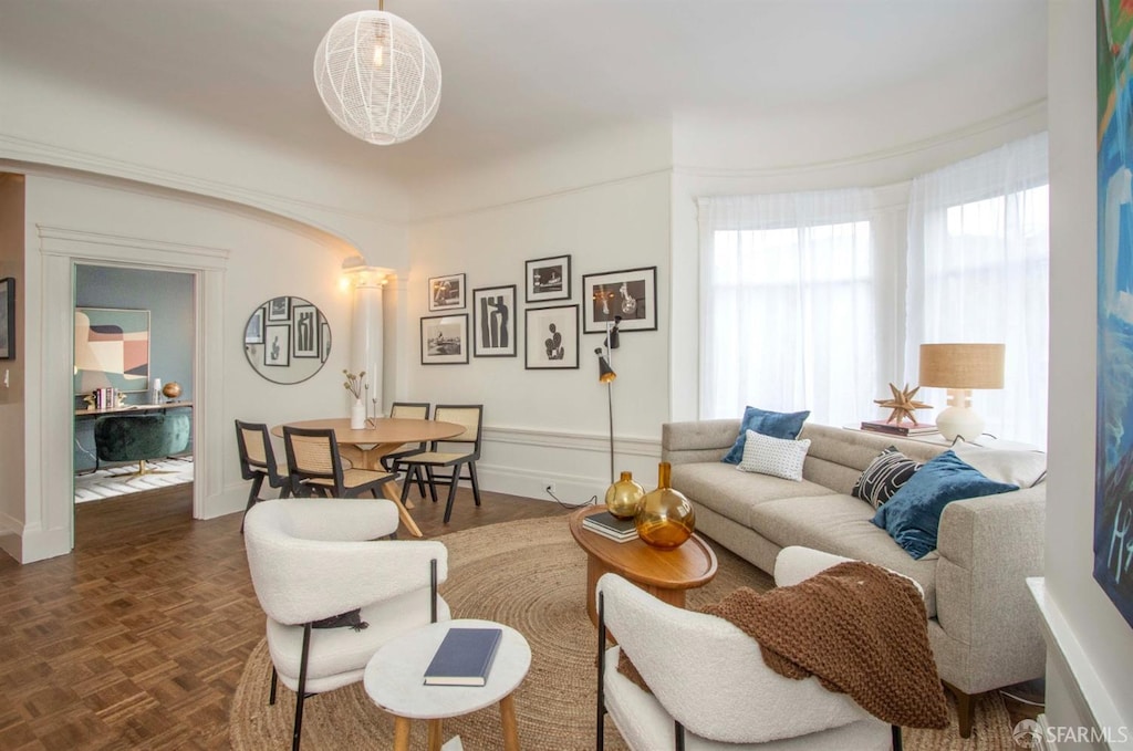 living room featuring dark parquet flooring and decorative columns