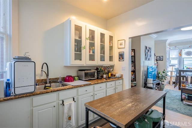 1380 Washington St, San Francisco, CA 94109 - kitchen featuring a sink, white cabinetry, glass insert cabinets, light wood finished floors, and ornamental molding