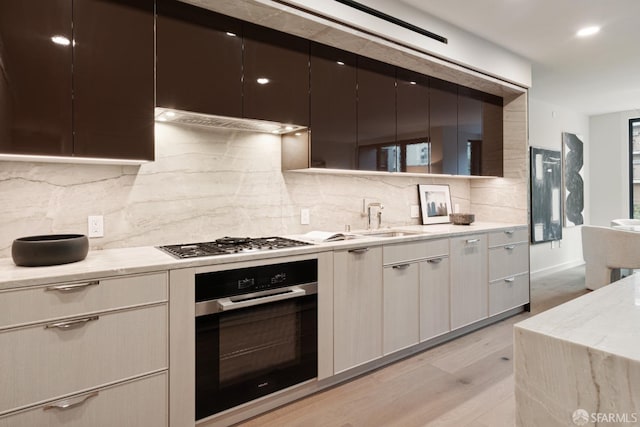 kitchen with stainless steel appliances, light hardwood / wood-style flooring, light stone countertops, and tasteful backsplash