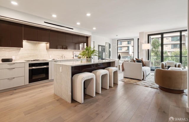 kitchen with tasteful backsplash, white cabinetry, a center island, light hardwood / wood-style floors, and stainless steel appliances