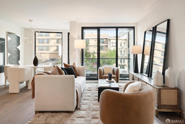 living room featuring light wood-type flooring, a wealth of natural light, and an inviting chandelier