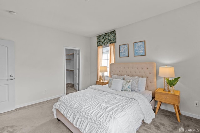 carpeted bedroom with a walk in closet and baseboards