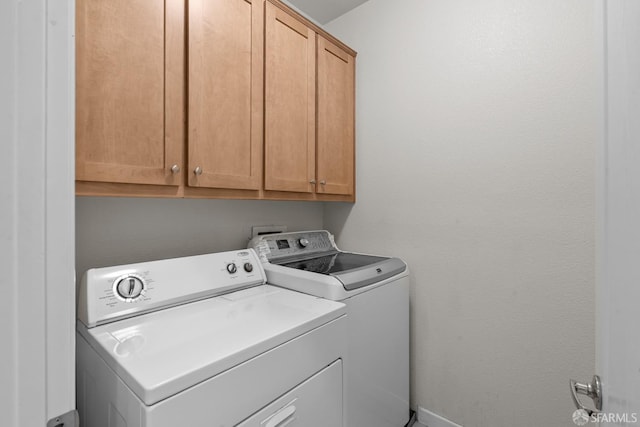 clothes washing area featuring washing machine and clothes dryer and cabinet space