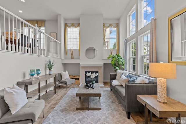 living area with recessed lighting, a fireplace, wood finished floors, and a towering ceiling