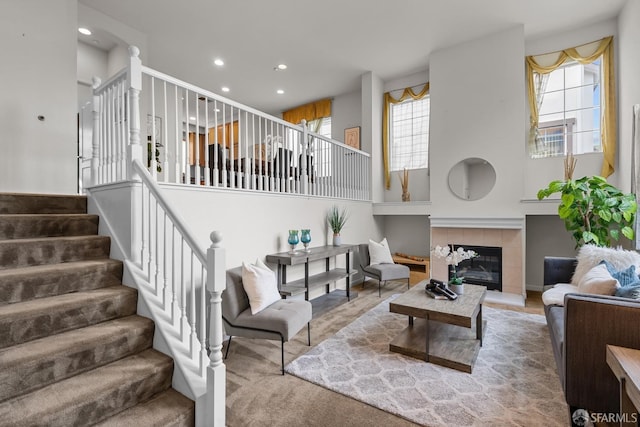 living room featuring recessed lighting, stairway, a high ceiling, and a tile fireplace