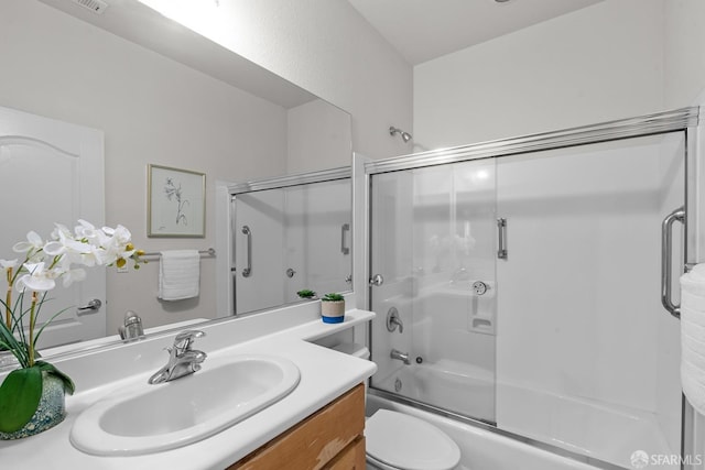 bathroom with toilet, vanity, and bath / shower combo with glass door