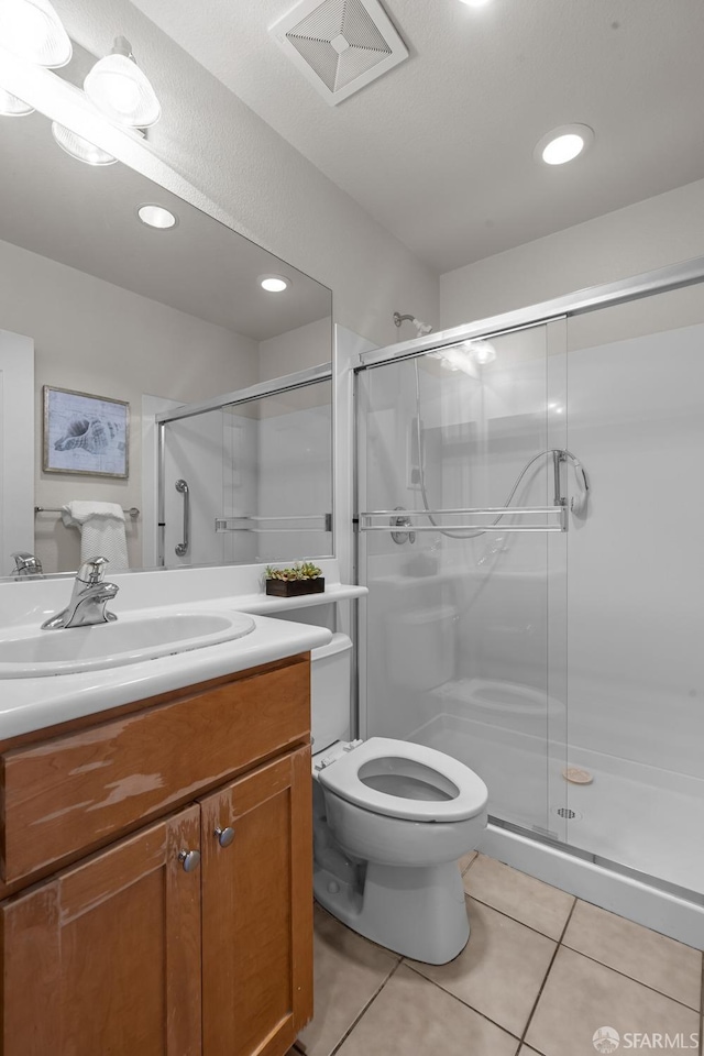 bathroom with tile patterned floors, visible vents, toilet, a stall shower, and vanity