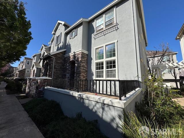 view of home's exterior with stucco siding, stone siding, and a residential view