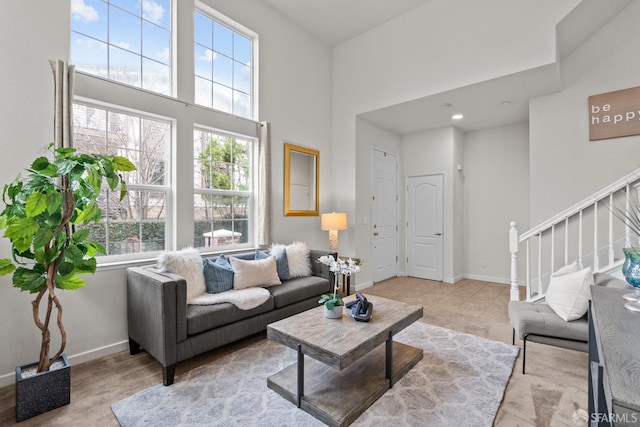 living area featuring tile patterned floors, stairway, baseboards, and a towering ceiling