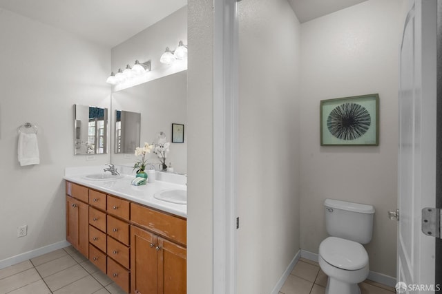 bathroom with baseboards, double vanity, a sink, tile patterned floors, and toilet