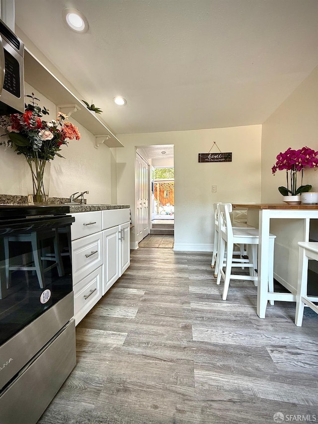 38002 Stenhammer Dr, Fremont, CA 94536 - kitchen with stainless steel range with electric stovetop, wood finished floors, white cabinets, baseboards, and recessed lighting