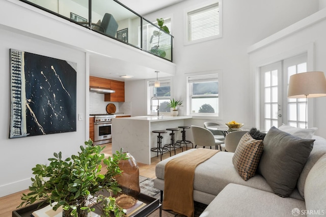 living room featuring a high ceiling, light wood-type flooring, and sink