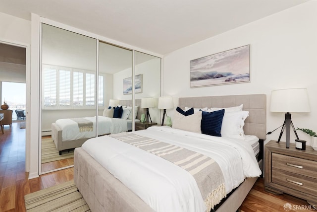 bedroom featuring a closet, a baseboard radiator, and hardwood / wood-style flooring