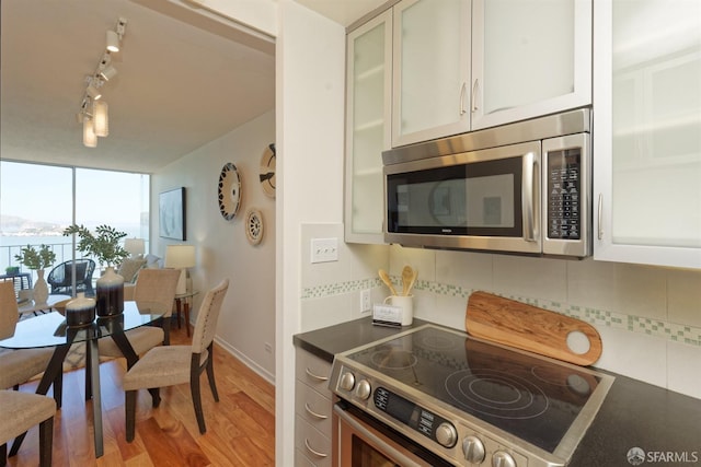 kitchen featuring decorative backsplash, stainless steel appliances, light hardwood / wood-style flooring, and white cabinets