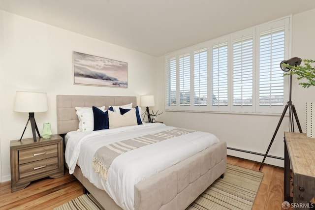 bedroom with light hardwood / wood-style flooring and baseboard heating