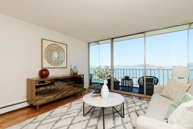 living room featuring baseboard heating, expansive windows, a water view, and wood-type flooring