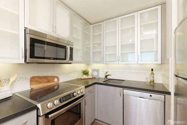 kitchen featuring backsplash, sink, white cabinets, and appliances with stainless steel finishes