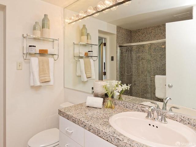 bathroom featuring vanity, an enclosed shower, and toilet