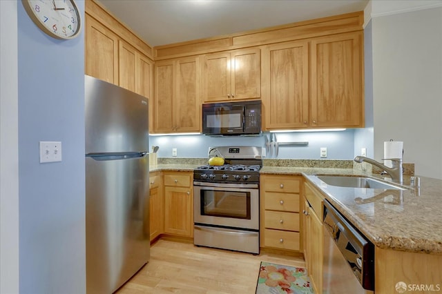 kitchen with sink, light hardwood / wood-style flooring, light brown cabinets, stainless steel appliances, and light stone countertops