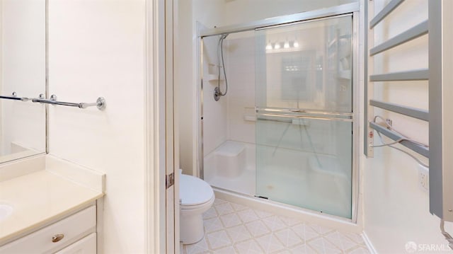 bathroom with vanity, a shower with door, and toilet