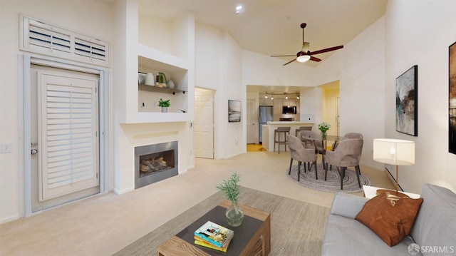 living room featuring ceiling fan, light colored carpet, and high vaulted ceiling