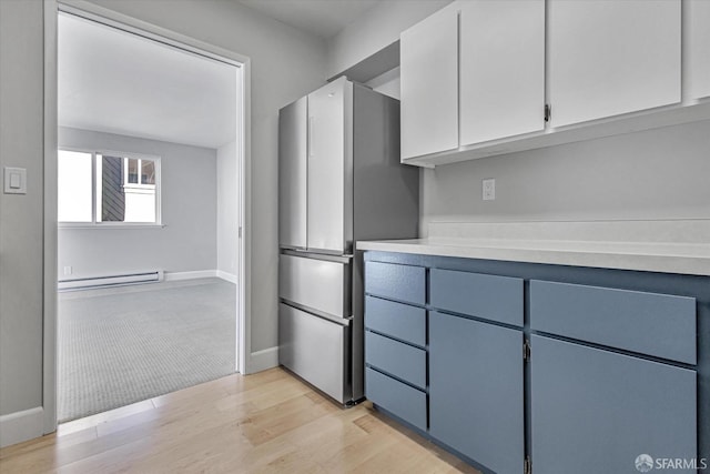 kitchen with white cabinets, a baseboard heating unit, stainless steel refrigerator, light wood-type flooring, and blue cabinets