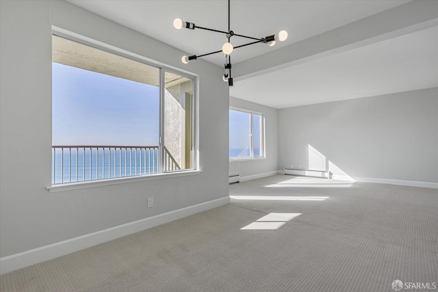 empty room with a water view, baseboard heating, carpet floors, and a chandelier