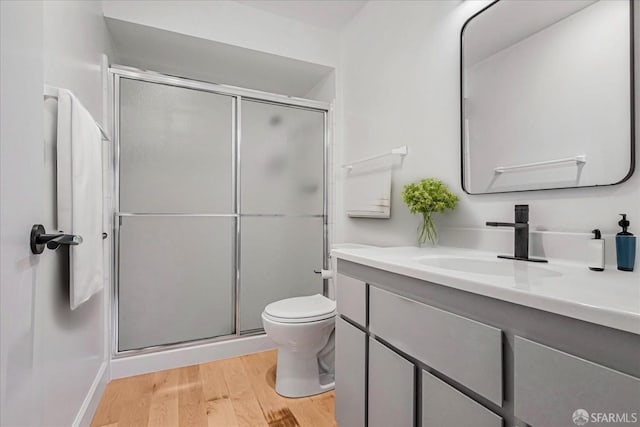 bathroom with walk in shower, vanity, wood-type flooring, and toilet