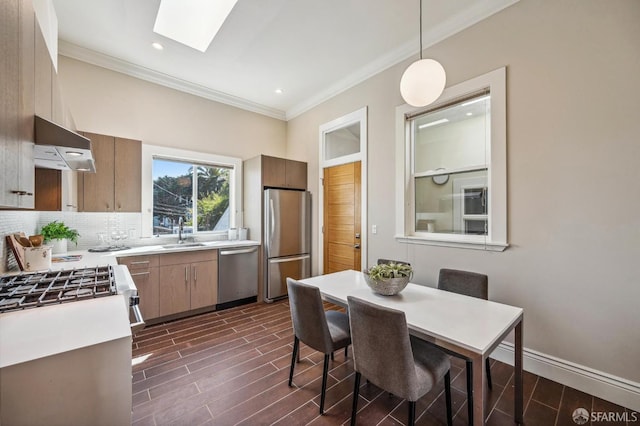 dining space featuring a skylight, sink, crown molding, and dark wood-type flooring