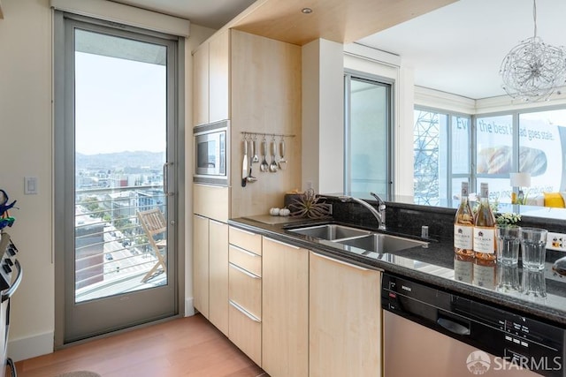 kitchen with dark stone countertops, appliances with stainless steel finishes, plenty of natural light, and light hardwood / wood-style flooring