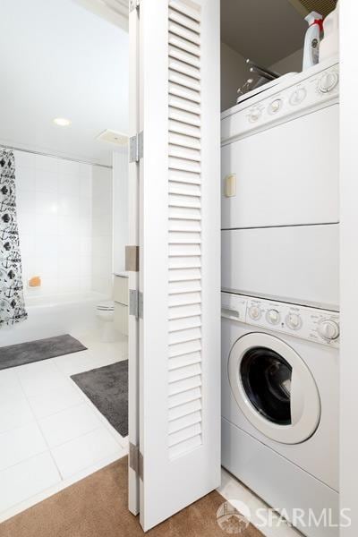 clothes washing area featuring stacked washer / drying machine and tile patterned floors