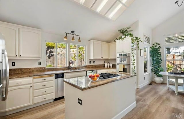 kitchen featuring a healthy amount of sunlight, a kitchen island, sink, and light hardwood / wood-style flooring