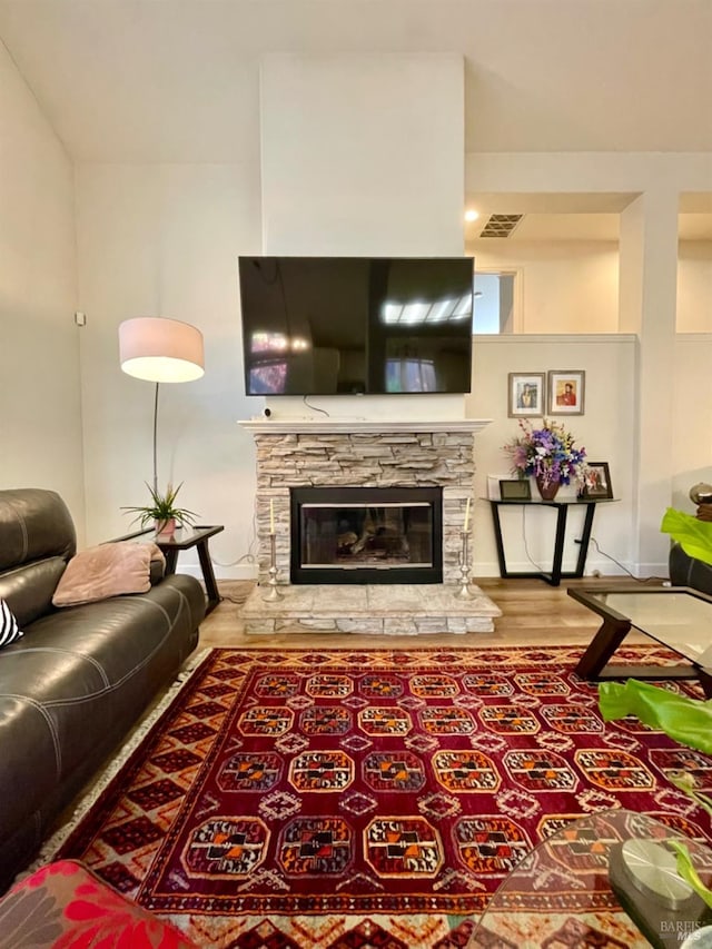 living room featuring a stone fireplace and hardwood / wood-style flooring