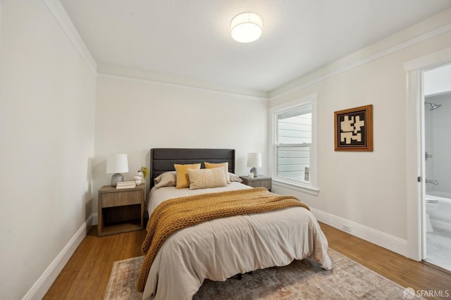 bedroom with hardwood / wood-style flooring, connected bathroom, and crown molding