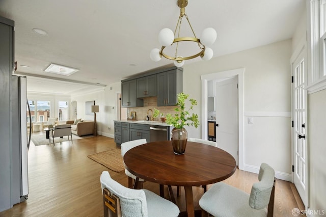 dining area featuring sink, light hardwood / wood-style flooring, and a chandelier