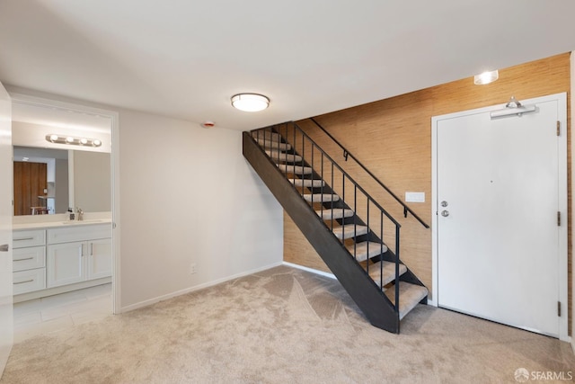 stairs featuring sink, wood walls, and carpet flooring